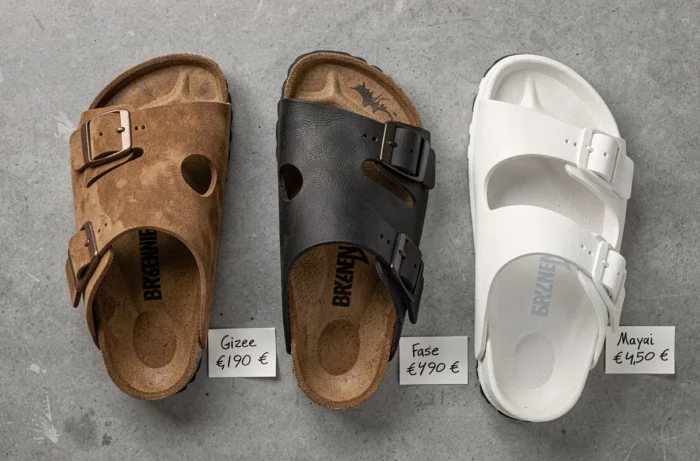 Comparatif de trois modèles de sandales Birkenstock avec étiquettes de prix en euros sur fond béton gris