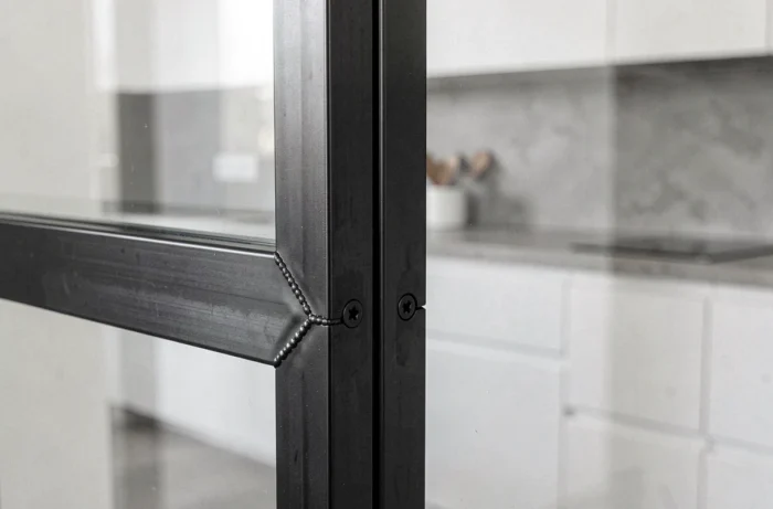 Détail de profilé en acier noir d'une cloison verrière modulable dans une cuisine moderne minimaliste